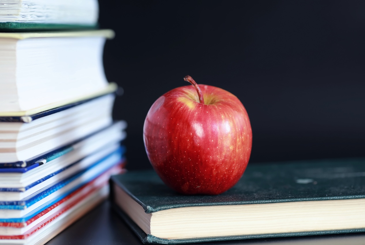 A stack of back to school books and an apple