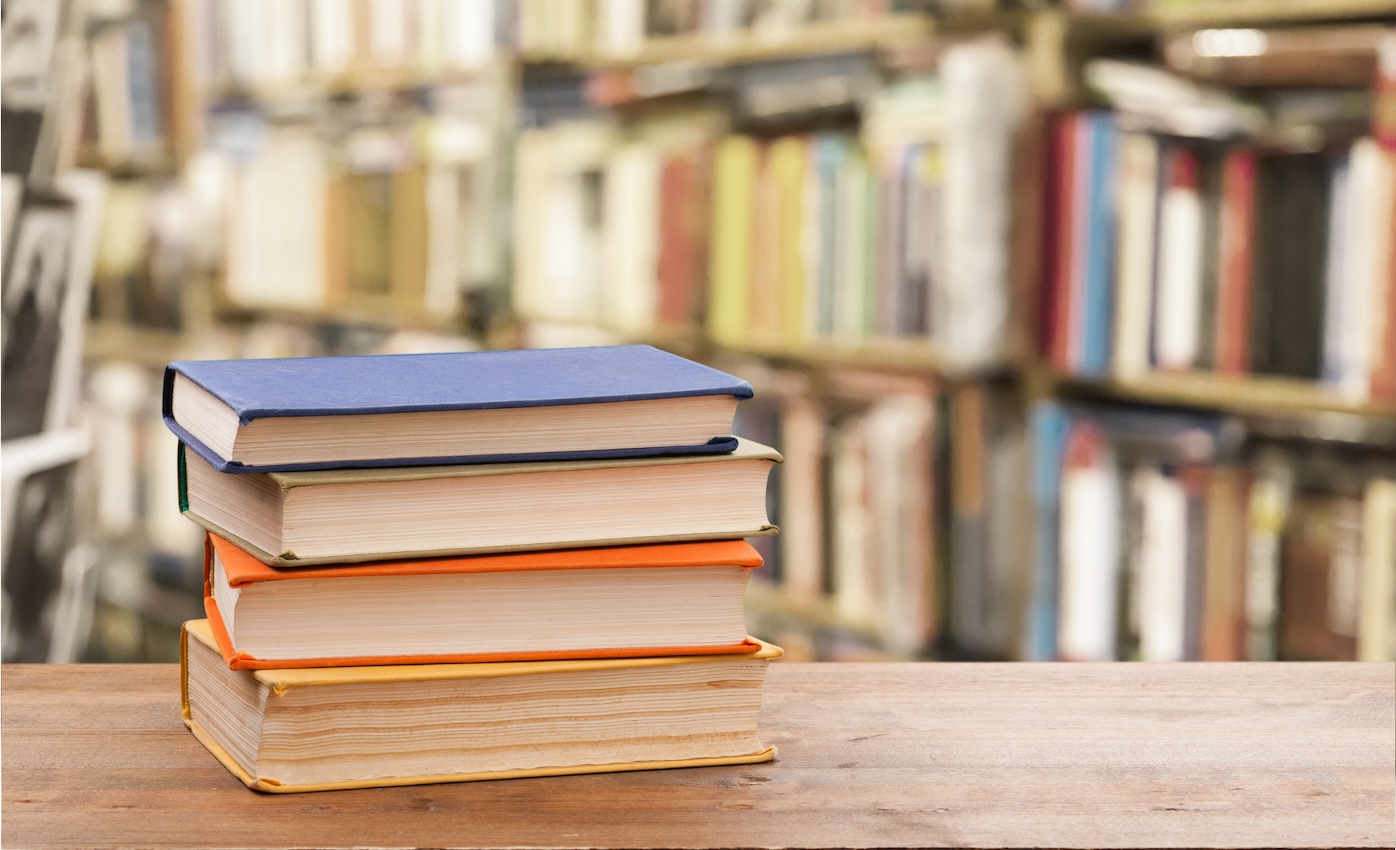 stack of books for sat and act prep in a library