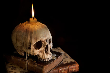 scary stories, creepy skull on a stack of books with candle burning on it