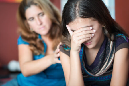 A mother comforts her crying teenage daughter